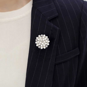 Close-up of pearl flower brooch with rhinestones on a dark blue pinstripe suit blazer