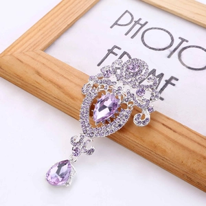 Macro shot of vintage silver brooch with purple teardrop crystals and floral rhinestones