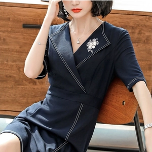 Detail of silver floral pearl brooch on dark blue V-neck dress with contrast stitching