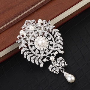 Macro view of silver floral brooch with pearls, crystals, and water drop pendant detail