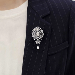 Detailed view of floral brooch with rhinestones and pearl drop on navy suit lapel