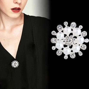 Detailed view of a silver floral brooch with white pearls and sparkling rhinestones