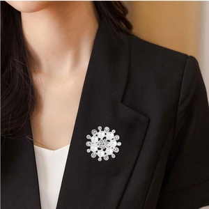 Detailed view of a flower brooch with pearls and crystals pinned on a black suit lapel