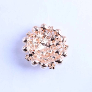 Detail of a gold-plated flower brooch back showing the pin closure and white pearls