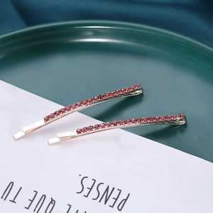 Detailed close-up of two silver hairpins with pink rhinestones on green ceramic