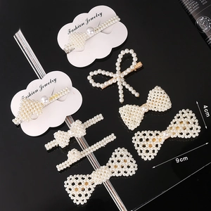 Elegant pearl hair clip set with bows and heart shapes on a glossy black background