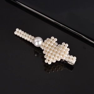 Macro detail of elegant white pearls on a silver metal hairpin base over black background