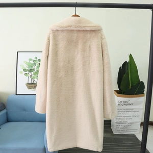 Détail de la texture douce de ce manteau en fausse fourrure beige suspendu