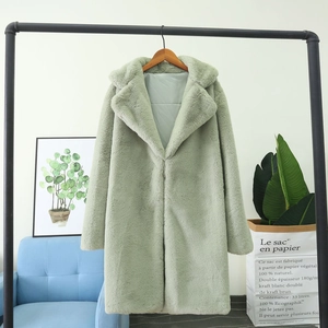 Détail de la texture d'un manteau en fausse fourrure vert menthe sur un cintre noir
