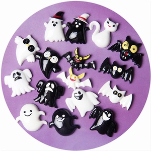 Halloween flat lay of 16 black and white ghost, bat, and cat resin accessories on purple background