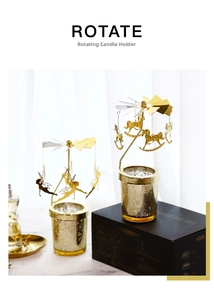 Close-up of golden rotating candle holder with carousel and angel charms on glass base