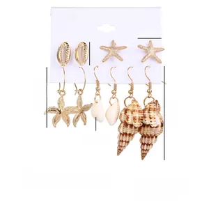 Detail of 6-pair gold ocean shell earrings set with starfish charms on display card