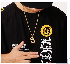 Dettaglio di una collana da uomo con ciondolo a forma di lettera S stile bambù dorato