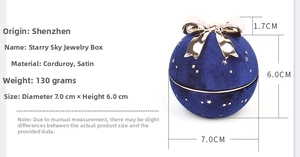 Macro shot of dark blue spherical jewelry box with gold bow and starry pattern