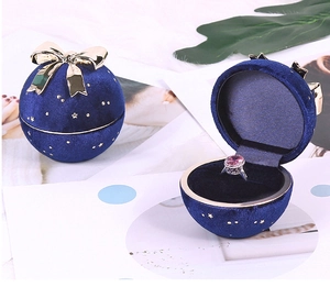 Blue velvet spherical jewelry box with a gold bow and star patterns shown open and closed