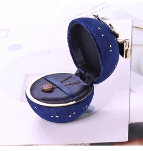 Macro view of blue spherical velvet jewelry box with gold bow and heart necklace
