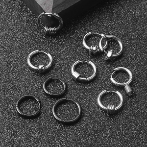 Macro view of silver and black stainless steel hoop earrings on a textured surface