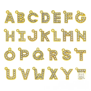 Macro detail of 15mm gold-plated alphabet charms with pavé crystals for DIY jewelry