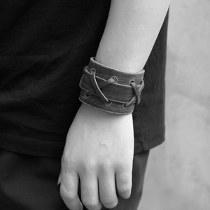 Détail d'un large bracelet manchette en cuir punk avec un design de laçage croisé tissé