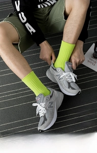Detail of neon green ribbed cotton crew socks paired with grey sneakers for street style