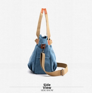 Side view of large denim blue canvas tote bag with adjustable strap and leather details