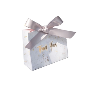 Detail of white marble gift box with a pink ribbon bow and gold Thank You text