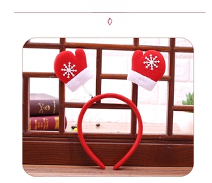 Christmas headband with red snowflake gloves on springs over a cozy wooden background