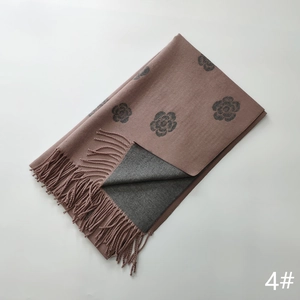 Detail of soft cashmere-like scarf with camellia jacquard pattern and fringe edges