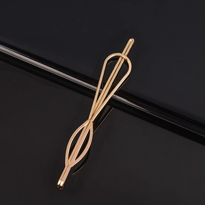 Barrette dorée minimaliste en forme de cœur et d'étoile sur une surface noire réfléchissante