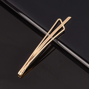 Pince à cheveux triangle minimaliste en métal doré brillant sur fond noir réfléchissant