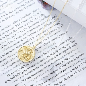 Macro detail of vintage 1901 S925 silver and gold queen coin relief pendants on text