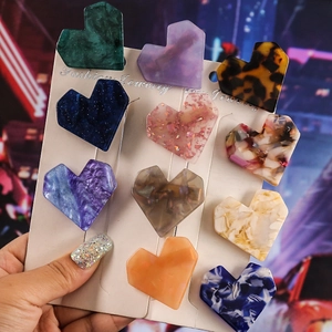 Colorful heart-shaped acetate hair clips set displayed on card against city bokeh