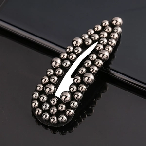 Close-up of gun-grey hair clip with metallic beads on black reflective surface