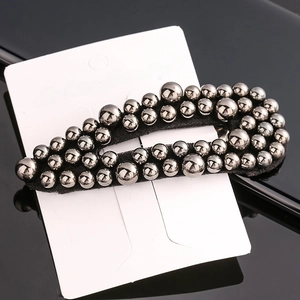Close-up of a black fabric hair clip with dense silver metallic bead embellishments