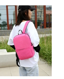 Outdoor view of a rose red casual backpack with wide straps and smooth fabric texture