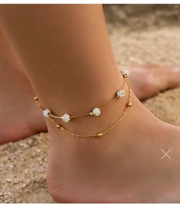 Double-layered gold anklet featuring sparkling crystal shamballa beads on a beach background
