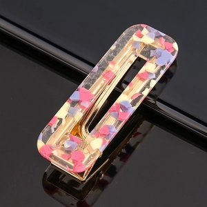 Detail of a rectangular hair clip featuring colorful acetate flakes in clear resin