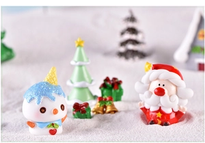 Macro shot of miniature resin Christmas figurines including Santa and snowman on snow