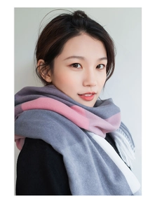 Close-up of thick plaid cashmere scarf in grey pink and white with tassel details