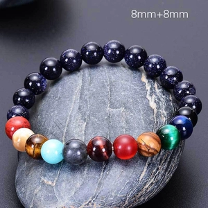 Close-up of solar system eight planets natural stone bracelet on raw grey rock