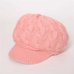 Detalle de gorro de punto trenzado rosa con visera mostrando textura cálida y gruesa