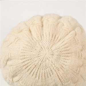 Vista superior de un gorro de punto trenzado beige que muestra la textura y los detalles