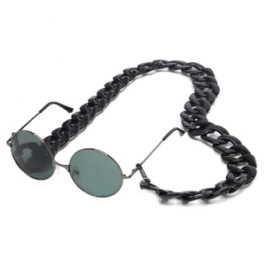 Close-up of black oversized acrylic chain links and retro round frame sunglasses