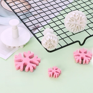 Macro detail of snowflake plunger cutters showing white plastic molds and fondant results