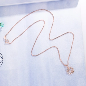 Elegant rose gold daisy wreath pendant necklace with sparkling crystals on light blue background