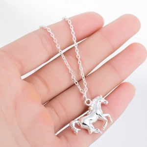 Gros plan détaillé d'un collier pendentif cheval en argent sur la paume d'une main