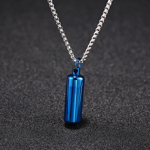 Detailed view of a blue metal capsule pendant on a silver steel chain over a dark background