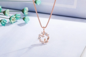 Macro view of rose gold daisy wreath pendant with sparkling zircons and delicate leaf charms