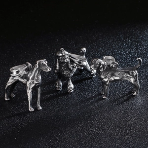 Three silver stainless steel poodle dog pendants for men on a textured black surface