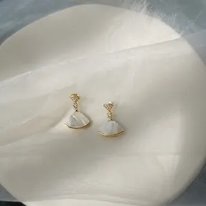 Detailed view of fan-shaped mother of pearl gold earrings with zircon accents